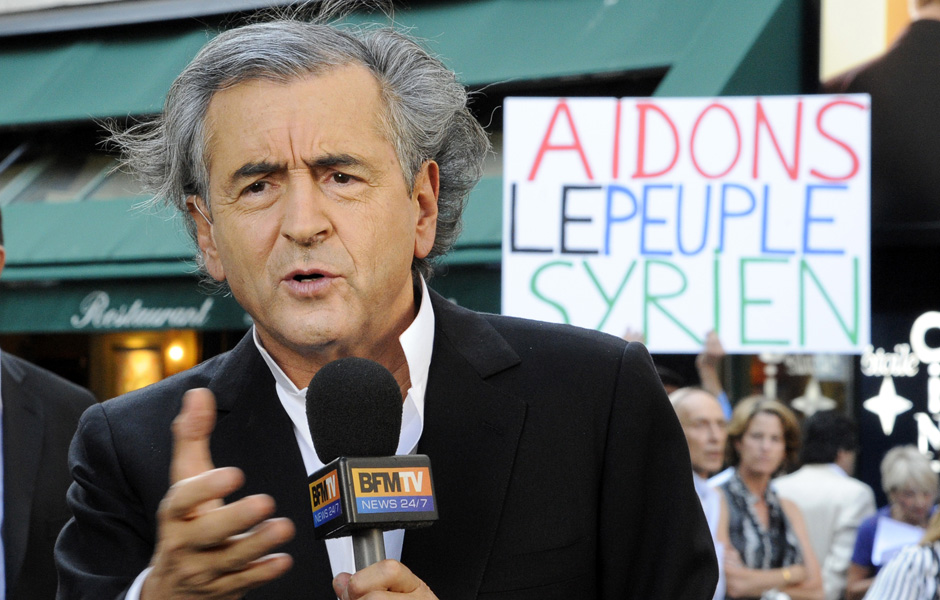 The shameless fraudulent "philosophe" Bernard-Henri Lévy—a proud Zionist—in a photo op designed to promote further aggression against the Syrian government. He has made a career out of imperialist shilling like this, and is naturally warmly received by all the top gatekeepers in the Western machinery of propaganda.